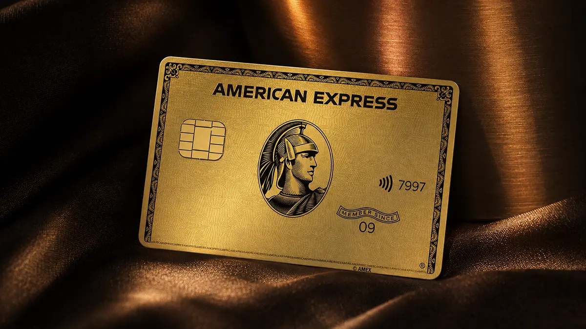 Cartão American Express dourado com o centurião em relevo, apoiado sobre tecido acetinado marrom e dourado