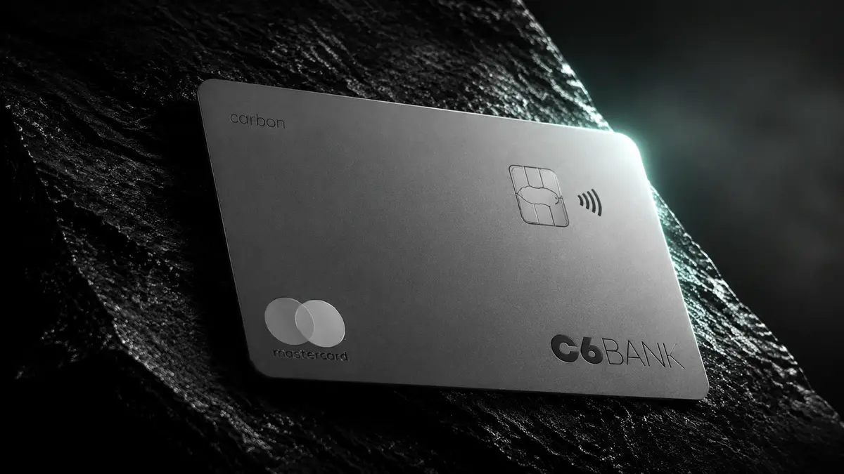 Cartão de metal prateado C6 Carbon com a palavra carbon gravada e logotipo Mastercard, sobre rocha escura
