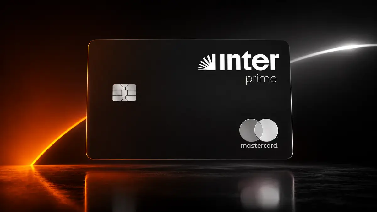 Cartão preto Inter Prime com o logotipo do Inter em branco e selo Mastercard prateado, sob um facho de luz laranja