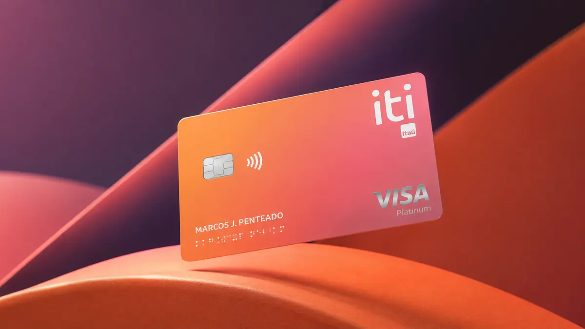 Cartão iti Itaú em degradê laranja e rosa, com selo Visa Platinum, nome em relevo e marcação em braile