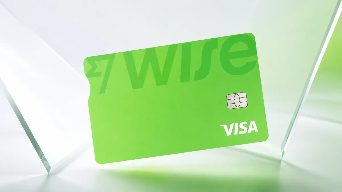 Cartão Wise verde-claro com o nome Wise em marca d'água, chip e a marca Visa, sobre fundo claro com painéis de vidro