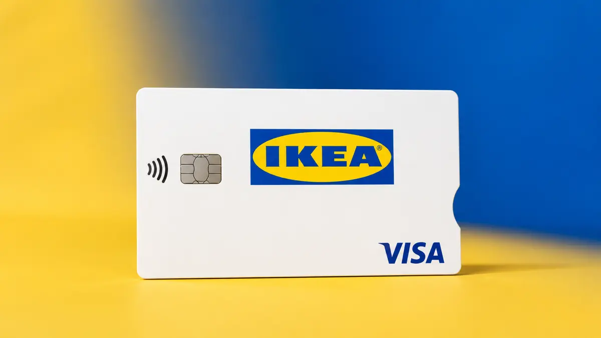 Tarjeta IKEA Visa blanca con el logotipo amarillo y azul de IKEA, chip y contactless, sobre fondo azul y amarillo