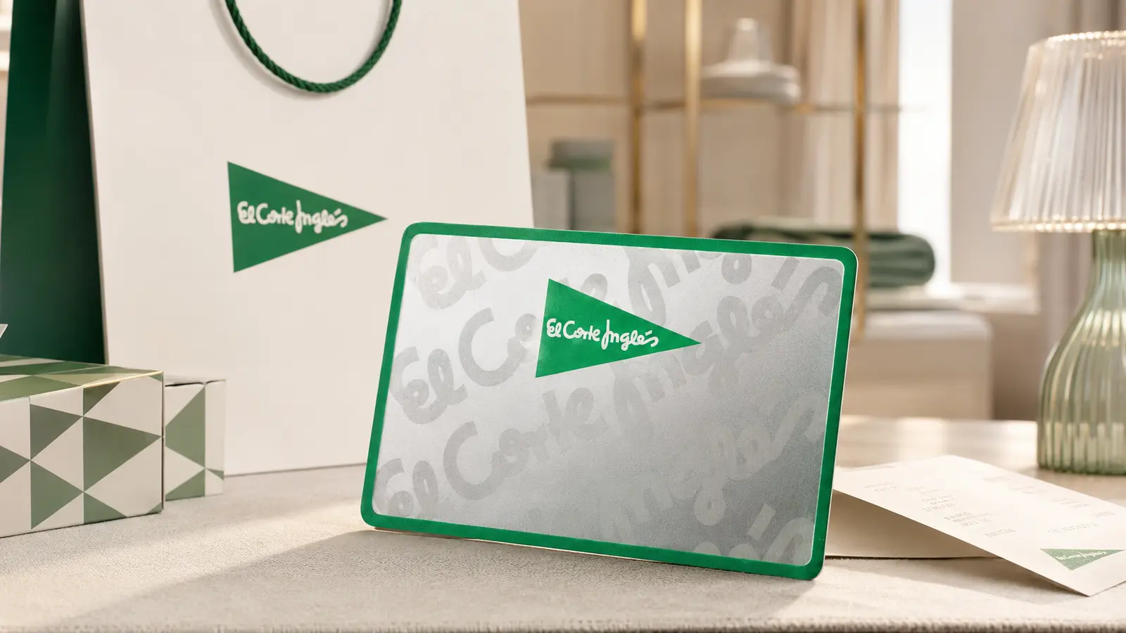 Cartão prateado e verde El Corte Inglés junto a um saco de compras, caixas e talão