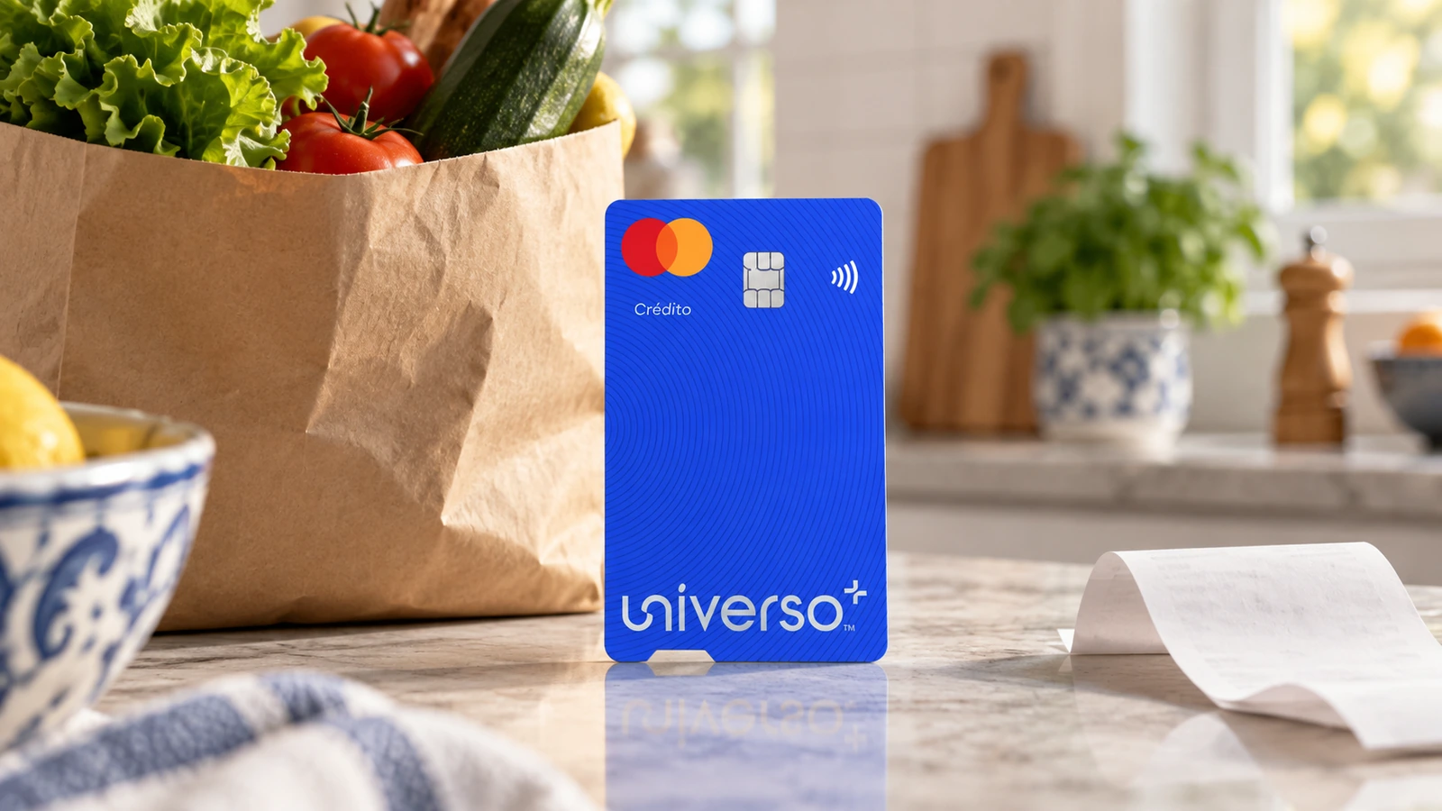 Cartão Universo+ azul junto a um saco de compras e um talão numa cozinha.
